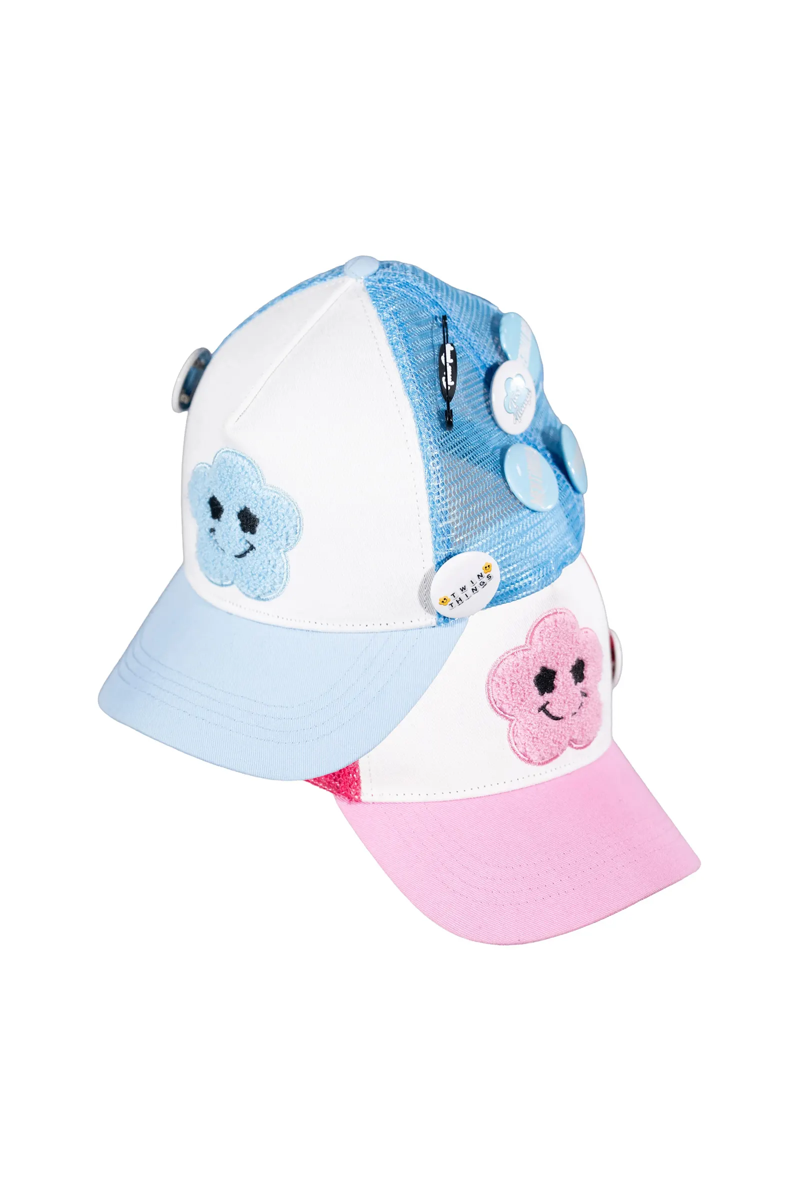Coppia di cappellini trucker Twin Things, azzurro e rosa, con patch nuvoletta sorridente in ciniglia e set di pin smaltati