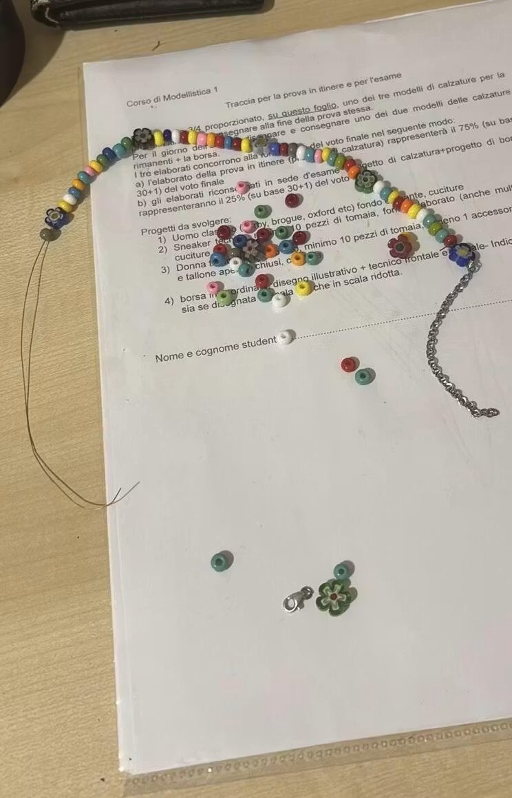 Collana Twin Things in fase di assemblaggio in atelier, perline e fiori millefiori su carta di lavorazione